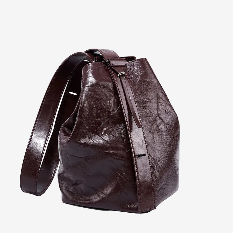 Cuirae burgundy glossy crinkled genuine leather bucket bag with wide shoulder strap, front angled view on white background