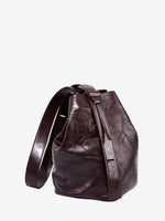 Cuirae burgundy glossy crinkled genuine leather bucket bag with wide shoulder strap, front angled view on white background