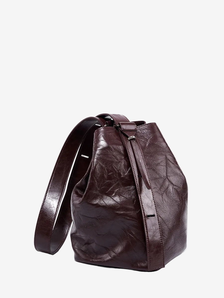 Cuirae burgundy glossy crinkled genuine leather bucket bag with wide shoulder strap, front angled view on white background