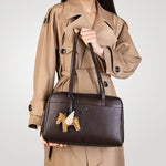 Woman holding a genuine leather Cuirae chocolate bowling bag with both hands, showing pony charm and smooth leather
