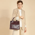 A woman handles the Cuirae coffee genuine leather tote bag  against a beige background