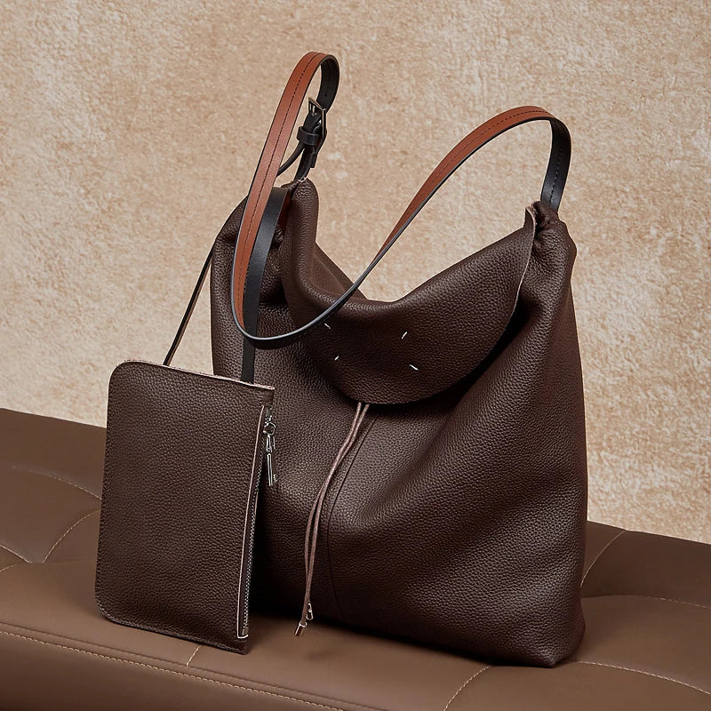 The Cuirae coffee genuine leather tote bag resting on a sofa in a lifestyle setting.