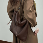A model wearing the Cuirae coffee genuine leather tote bag, worn over the shoulder with the back facing forward
