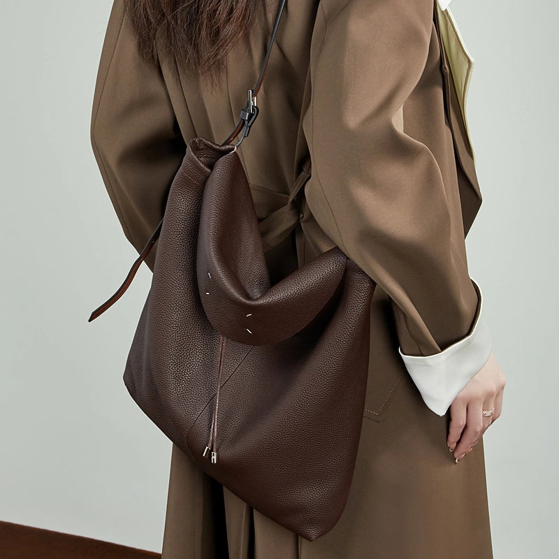 A model wearing the Cuirae coffee genuine leather tote bag, worn over the shoulder with the back facing forward
