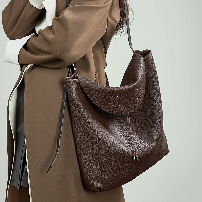 A woman wearing the Cuirae coffe genuine leather tote bag on her shoulder.