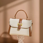 Cuirae color block genuine leather shoulder bag on clear stand, warm light background highlighting pebbled leather texture
