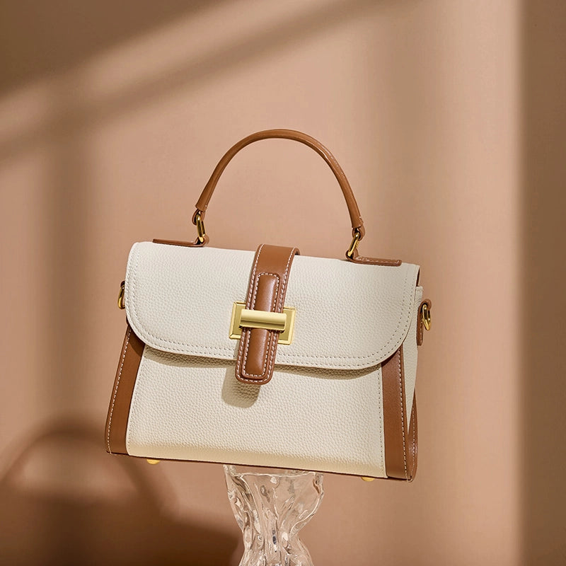 Cuirae color block genuine leather shoulder bag on clear stand, warm light background highlighting pebbled leather texture
