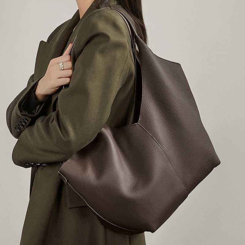 A close look at the Cuirae coffee genuine leather tote bag worn on the shoulder.