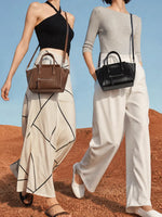 Two women walking outside wearing the Cuirae black and brown genuine leather handbags.