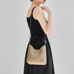 Side view of Cuirae gray genuine leather bucket bag worn on shoulder, showing detachable shoulder strap