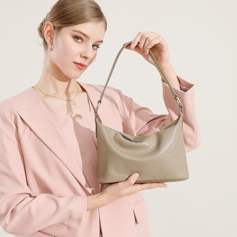 Woman holding Cuirae gray genuine leather hobo bag, displaying adjustable shoulder strap and silver hardware