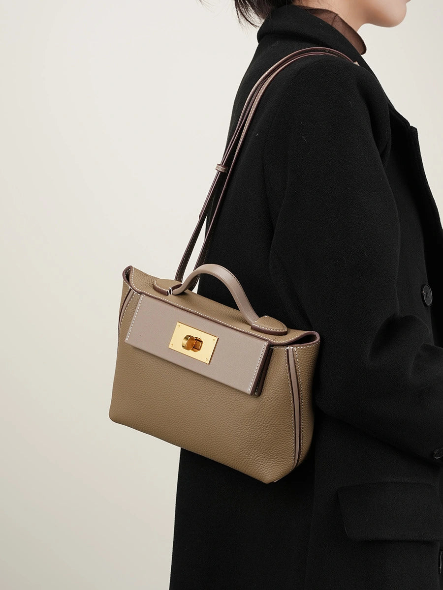 Woman wearing Cuirae gray leather flap kelly crossbody bag on shoulder, side view with black coat outfit