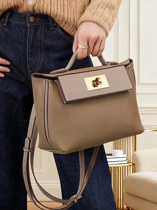 Model holding Cuirae gray pebbled leather flap kelly crossbody bag by top handle, indoor home scene showing gold turnlock