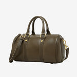 Cuirae green genuine leather barrel crossbody bag with gold hardware and detachable strap, side view on white background