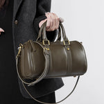 Closeup of Cuirae green genuine leather crossbody bag held by hand, showing gold hardware and stitching details