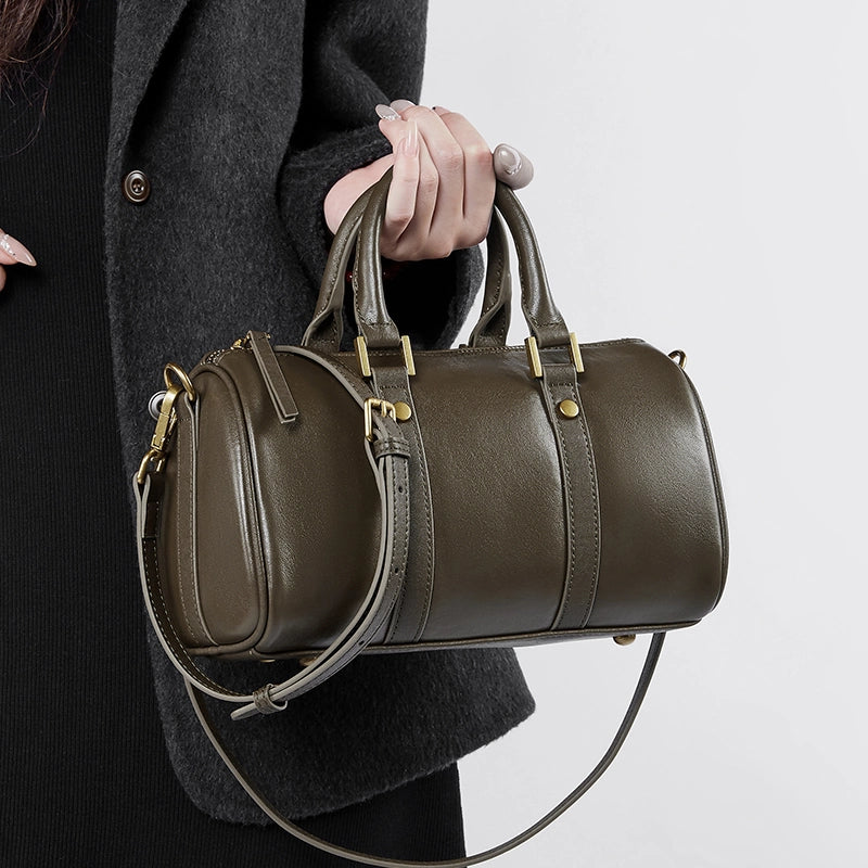 Closeup of Cuirae green genuine leather crossbody bag held by hand, showing gold hardware and stitching details