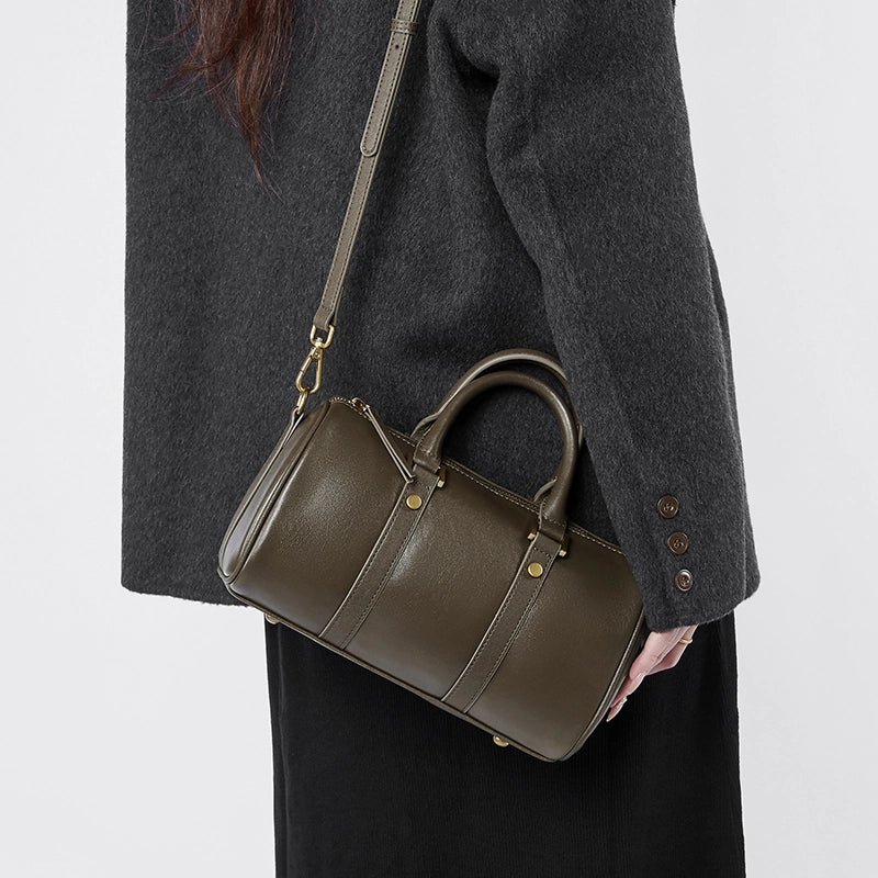 Woman wearing Cuirae green leather barrel crossbody bag, angled view showing versatile styling options