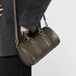 Model wearing Cuirae green leather barrel crossbody bag, side view showing detachable strap and classic shape