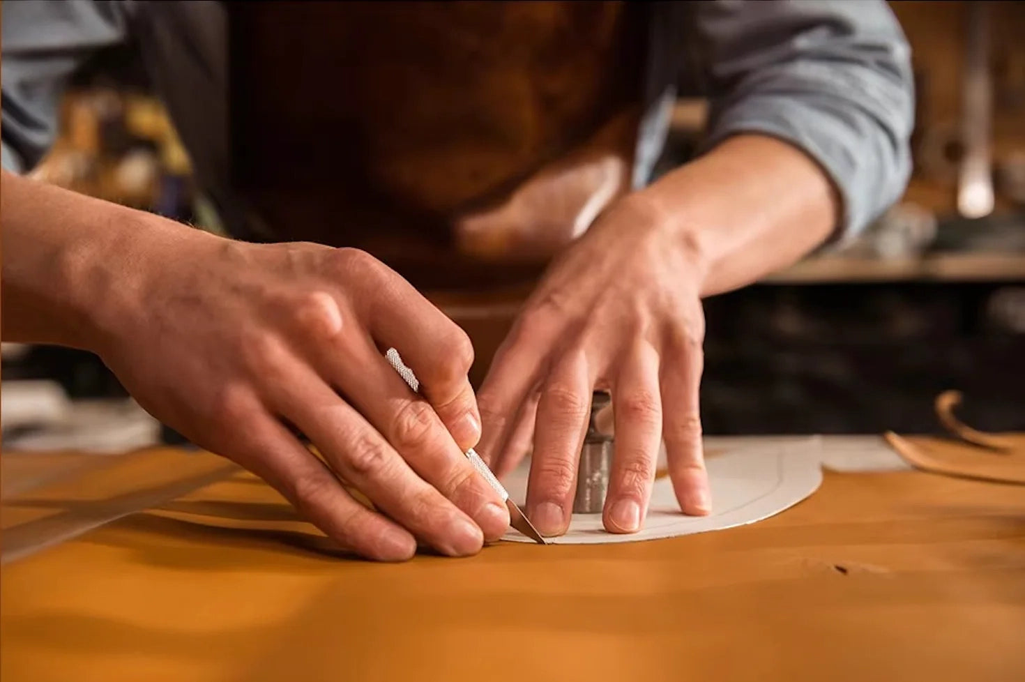 Close up of an artisan's hands carefully cutting Cuirae 100% real leather. Handcrafted to be built to last.