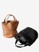 Brown and black leather bucket bags displayed together, showing their rounded silhouettes and cross-seam detailing