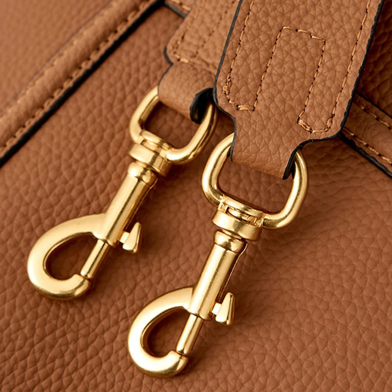 Gold-tone swivel clips and stitching on the brown leather bucket bag’s detachable strap