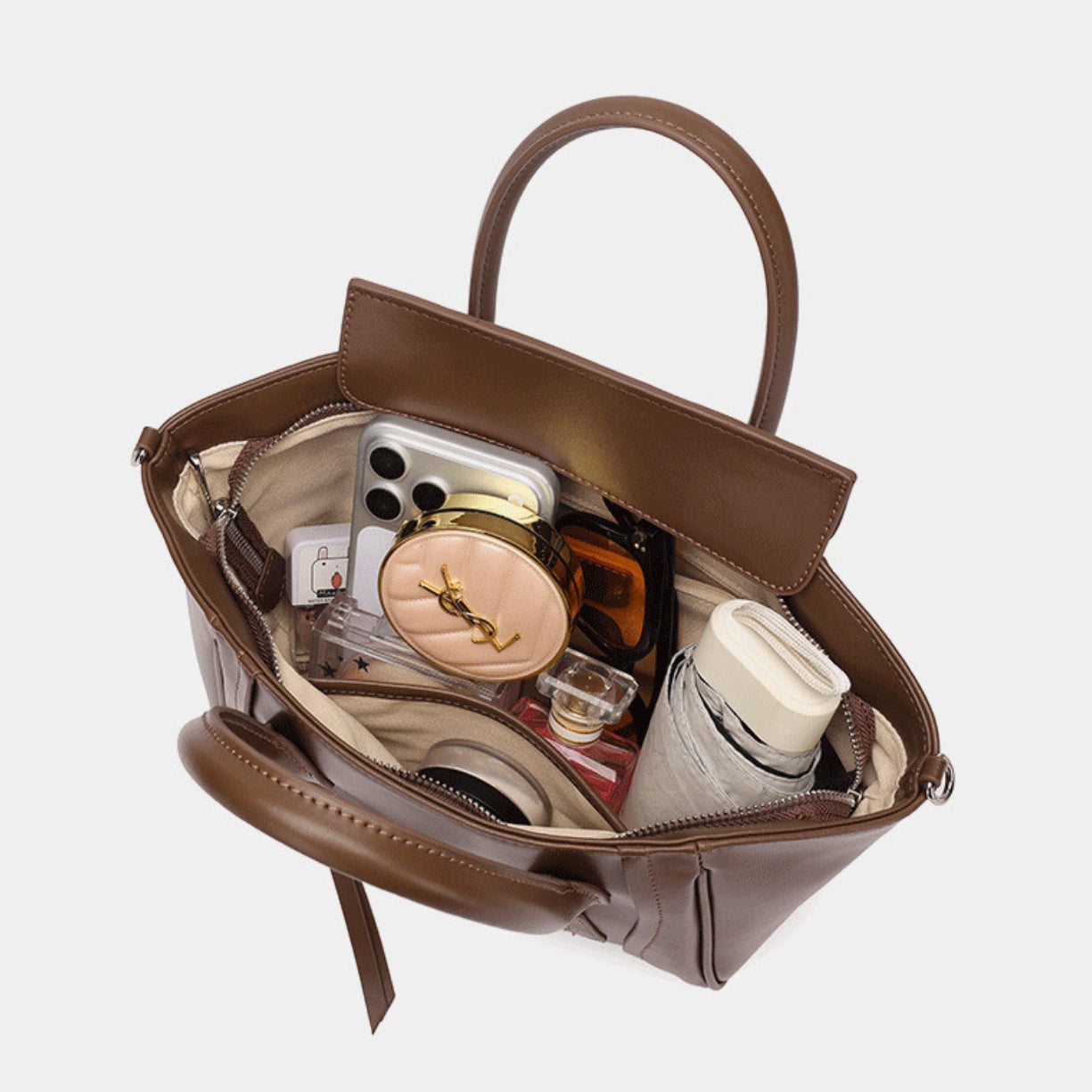 Inside view of the Cuirae leather bag holding a phone, makeup, and an umbrella with ease.