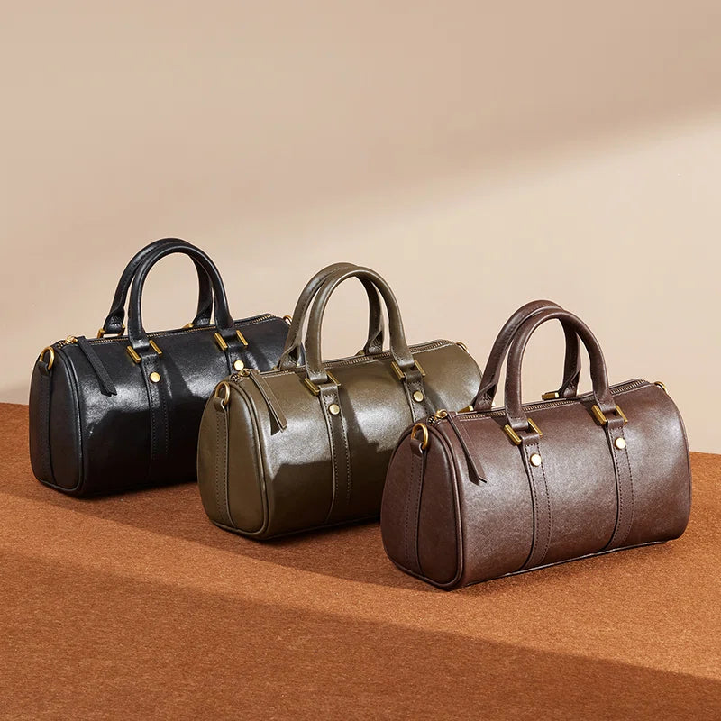 Three Cuirae genuine leather crossbody bags in black, olive green, and dark brown resting in a row on a brown surface.