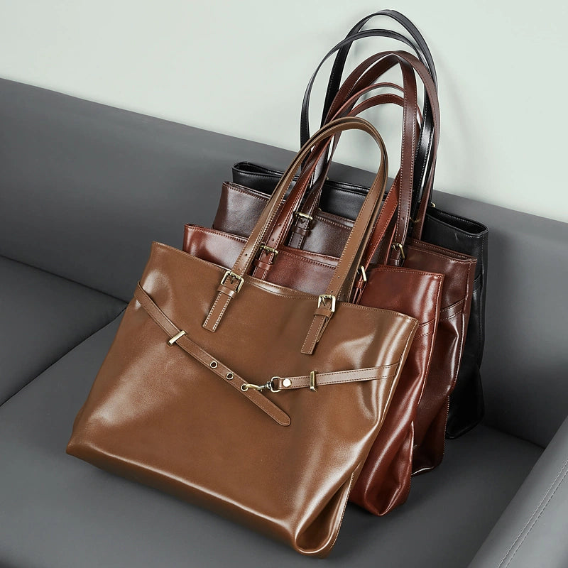 Four Cuirae genuine leather handbags in various shades of brown and black resting in a row on a grey sofa.