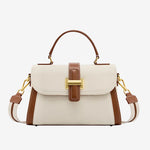 Cuirae off white and brown pebbled leather shoulder bag with gold lock hardware and top handle, front view on white background
