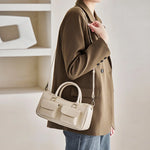 Model wearing Cuirae off white genuine leather bowling bag on shoulder, side view showing double front pockets and detachable strap