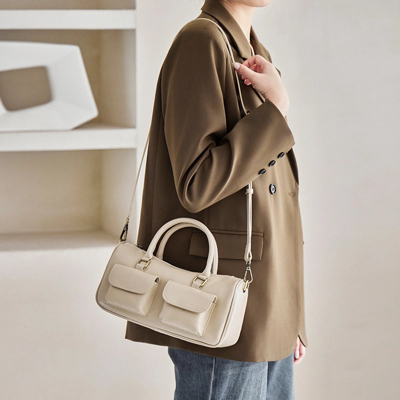Model wearing Cuirae off white genuine leather bowling bag on shoulder, side view showing double front pockets and detachable strap