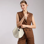 Woman wearing a Cuirae off-white leather slouchy bucket bag on her arm, angled view showing soft silhouette
