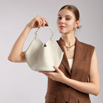Model holding Cuirae off-white pebbled leather bucket bag, front view showcasing adjustable top handle