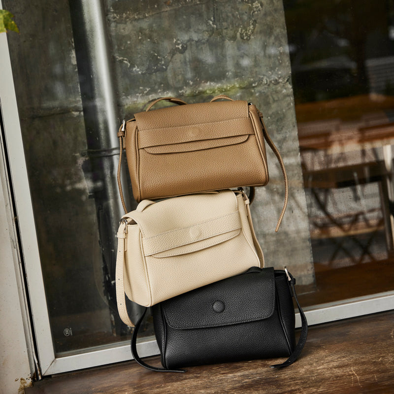 Cuirae pebbled leather flap shoulder bag shown in black, ivory, and gray