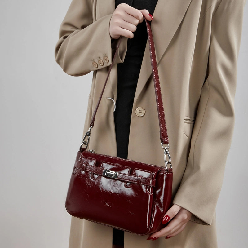 Model holding Cuirae red glossy leather crossbody bag, front view showcasing turnlock detail and sleek texture