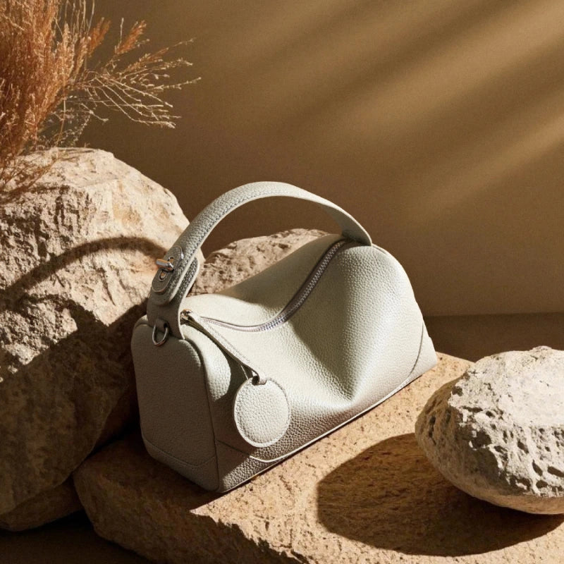 Cuirae stone genuine leather bowling bag on natural stone, warm natural light showing pebbled leather texture