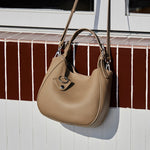 Cuirae taupe genuine leather bucket bag on red and white tile window sill, natural light showing pebbled texture
