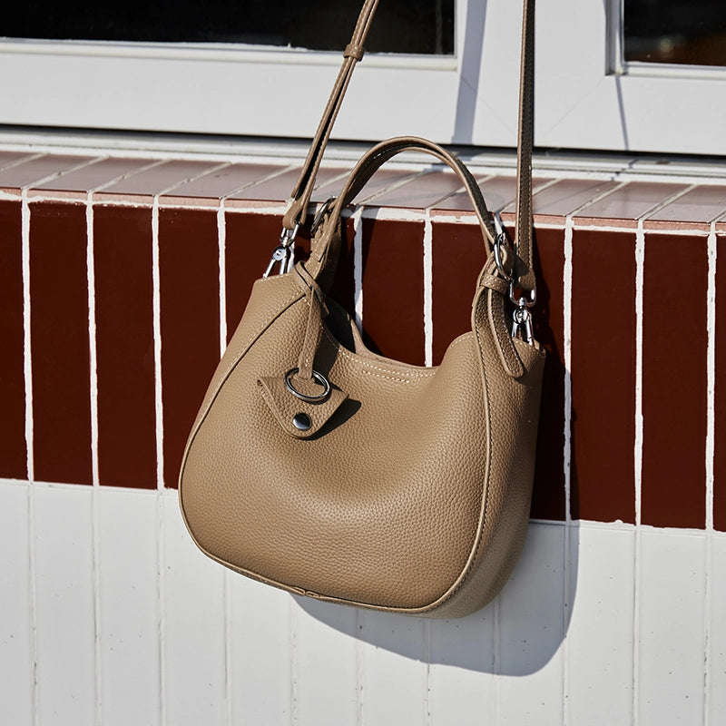 Cuirae taupe genuine leather bucket bag on red and white tile window sill, natural light showing pebbled texture