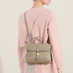 Back view of Cuirae taupe genuine leather flap handbag worn crossbody, showing top handle and contrast stitching
