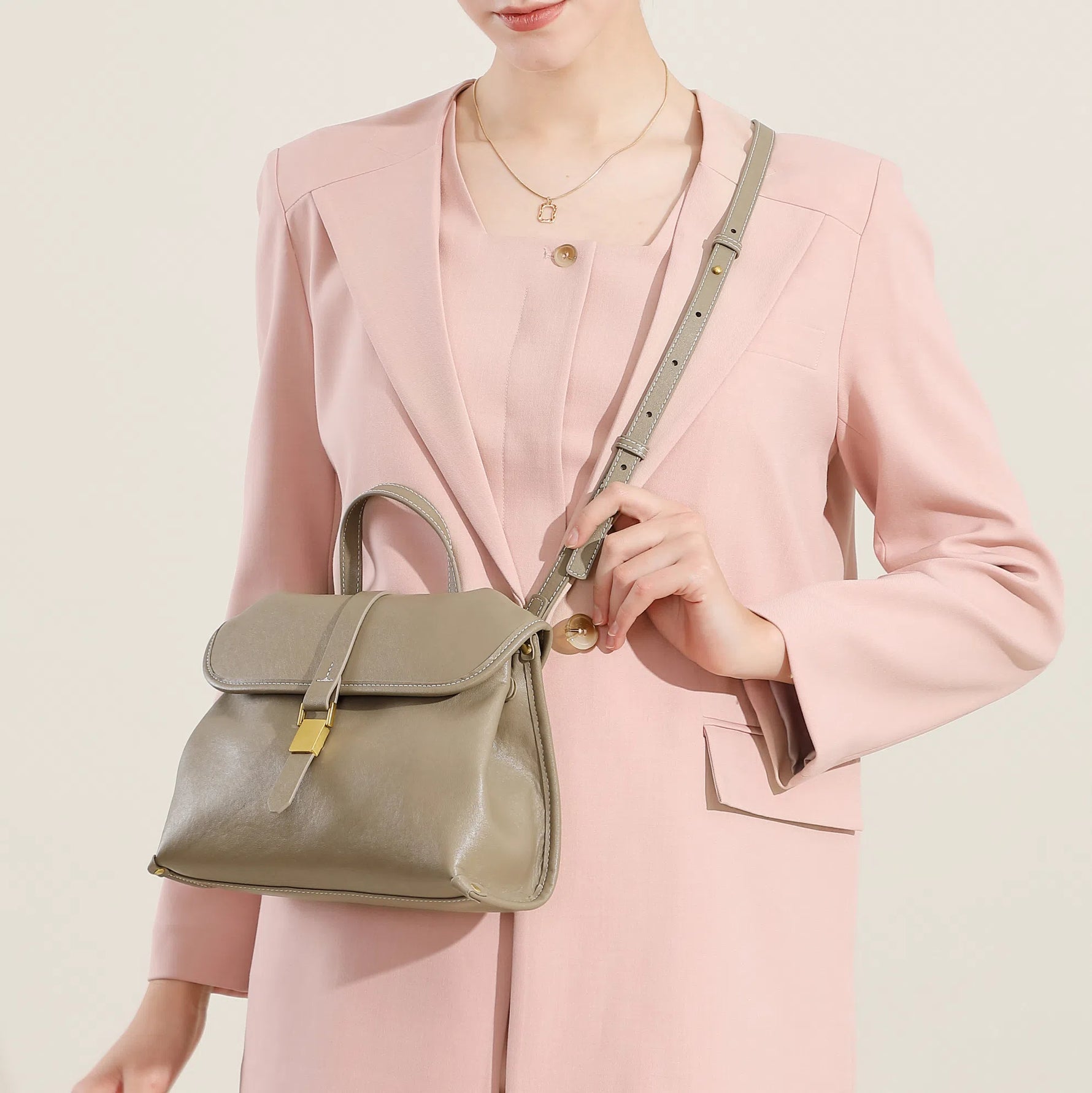 Model wearing Cuirae taupe genuine leather flap handbag crossbody, front view showing gold buckle and detachable strap