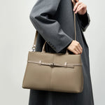 Model wearing Cuirae taupe genuine leather handbag on shoulder, side view showing detachable crossbody strap