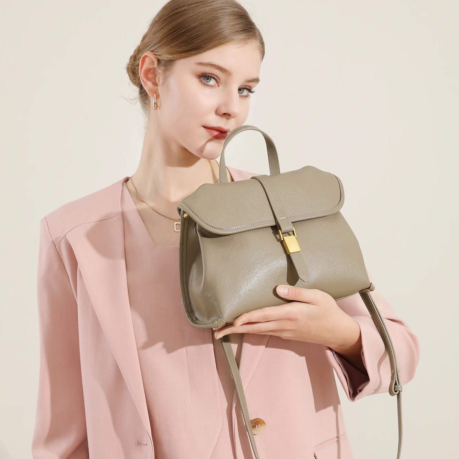 Woman holding Cuirae taupe genuine leather top handle bag, side view showing smooth leather texture