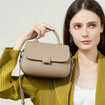 Woman carrying Cuirae taupe genuine leather mini shoulder bag by top handle, front view