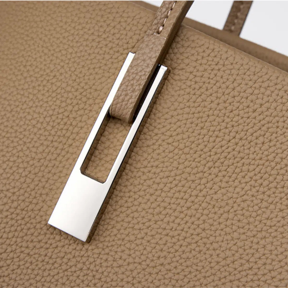 Close-up of the silver-tone handle attachment on a taupe pebbled leather tote