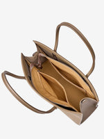 Interior of a taupe leather tote showing the zippered main compartment, inner pockets, and open side compartments