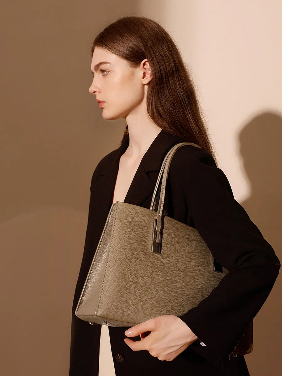 Side view of a model wearing a taupe pebbled leather tote over her shoulder