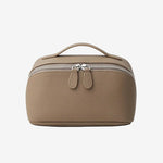 Cuirae taupe pebbled genuine leather makeup bag with top handle and double zipper, front view on white background.
