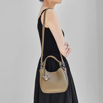 Side view of Cuirae taupe pebbled leather bucket bag worn on shoulder, showing silver hardware details