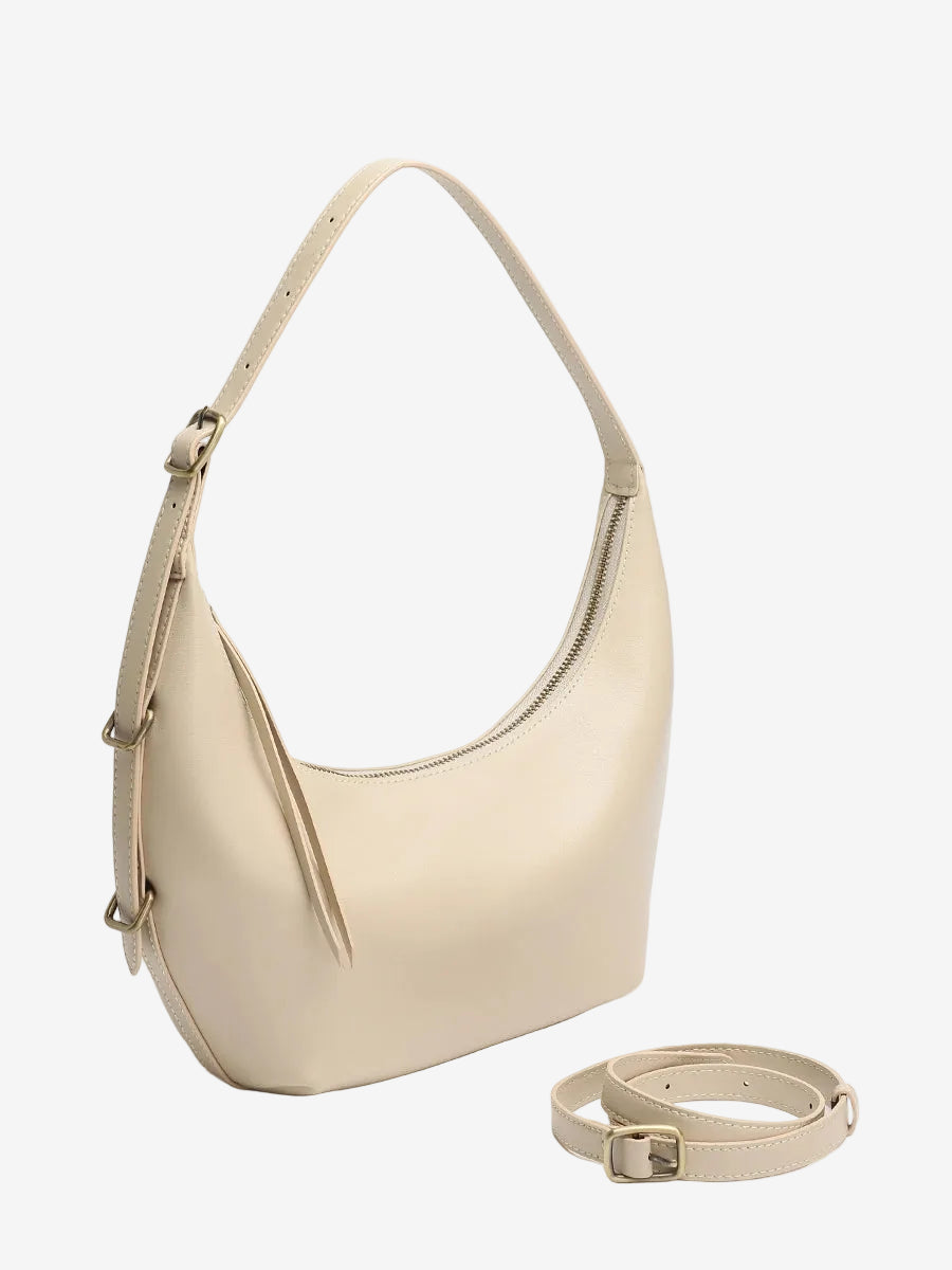The Cuirae white genuine leather handbag sitting next to an extra strap on a plain white background.