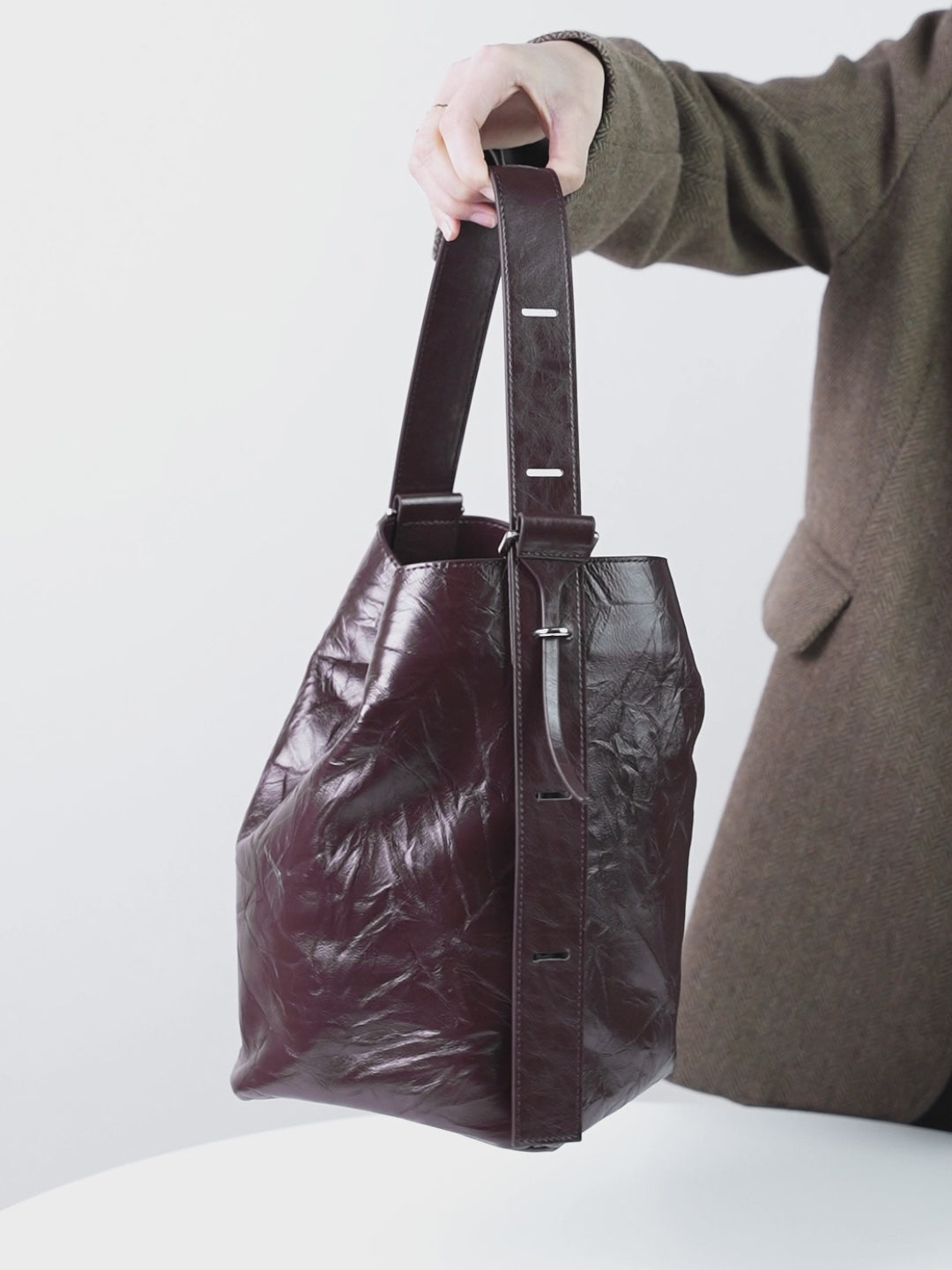 A dynamic showcase of the Cuirae genuine leather bucket bag, highlighting its appearance up close and the details and capacity, as well as how the models demonstrate its versatility with various outfits.
